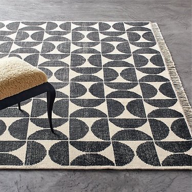 black and white geometric area rug with fringe on gray floor