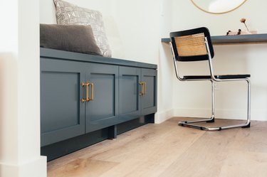 Wood laminate flooring next to blue bench and black chair