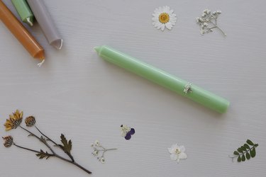 Small white pressed flower placed on top of green taper candle
