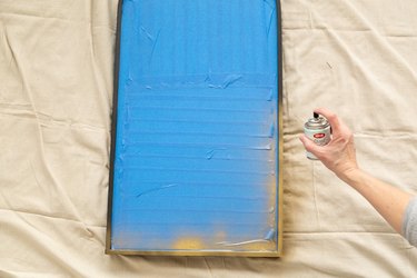 spray painting a mirror frame in gold