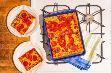 blue small sheet pan with pizza on stovetop