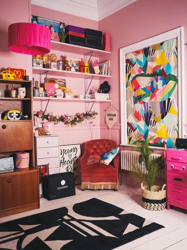 pink maximalist home office with large bookcase and vibrant wall art, red lounge chair in the corner