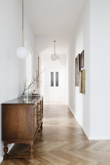 Hallway with wood floors, white globe lamps, antique console table.