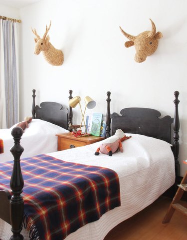 twin kids bedroom with brass table lamp and rattan animal heads