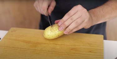 person cutting a line around the center of a potato