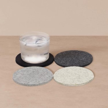 four wool coasters in muted colors, one with glass on top