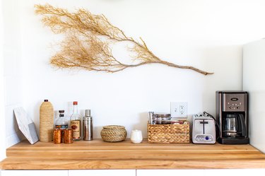 Butcher-Block countertop in kitchen with toaster and coffe maker on it and a branch hanging above it
