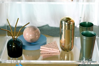 metallic cups and decor on a bar cart shelf