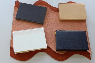 Four books holding two wavy cork pieces flat while glue dries