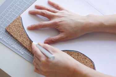 Cutting out template shape on cork with craft knife