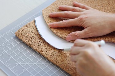 Cutting around edges of template on cork with a craft knife
