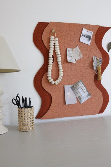 DIY wavy cork bulletin board with various items pinned to it