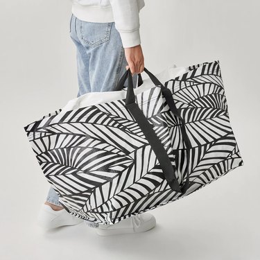 person wearing jeans and holding a black and white patterned bag