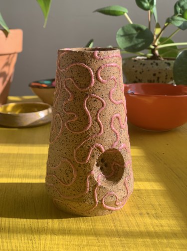 ceramic piece in terra cotta color with squiggly line design