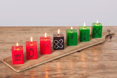 Kwanzaa decorations, red, green, and black kwanzaa cube candles on a wooden board