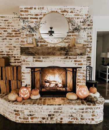 fall fireplace mantel idea with weathered books and an assortment of pumpkins