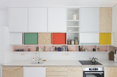 Multi colored cabinets, induction stove, white counters.