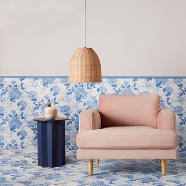 pink chair in front of blue floral wallpaper