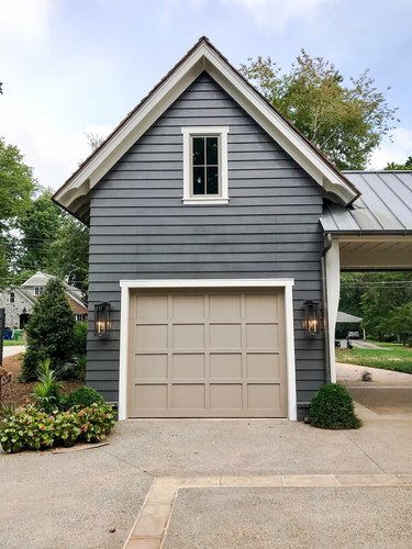 Farmhouse garage door in beige with dark gray exterior and lantern sconces