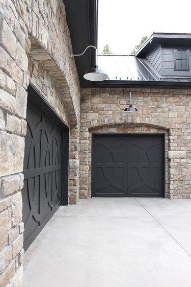 Farmhouse garage doors with black circular patterns and stone exterior