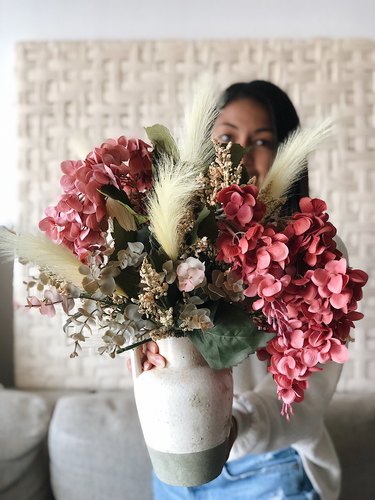 YouTuber Nastazsa holding faux flower arrangement.