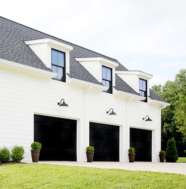 Farmhouse garage doors in black with black barn lights and white exterior
