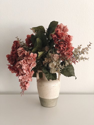 Faux flowers in a rustic vase.