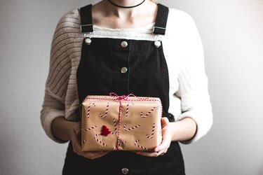 person in black overalls holding present with candy cane wrapping paper