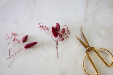 Bundling berry-colored dried flowers together with wire
