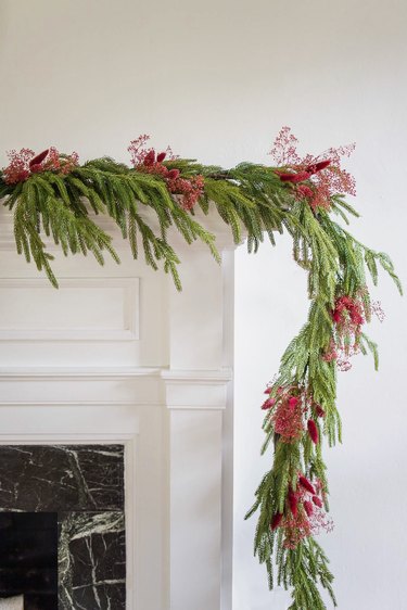 Asymmetrical mantel garland decorated with berry-colored dried floral sprays