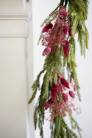 Asymmetrical mantel garland decorated with berry-colored dried floral sprays