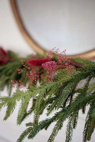 Dried berry-colored florals tucked into mantel garland