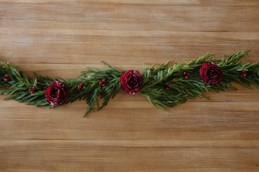 Holiday garland table runner decorated with burgundy ranunculus and berries