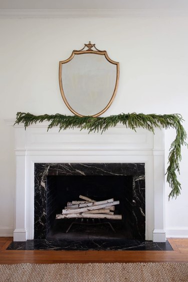 Pine garland arranged asymmetrically on fireplace mantel