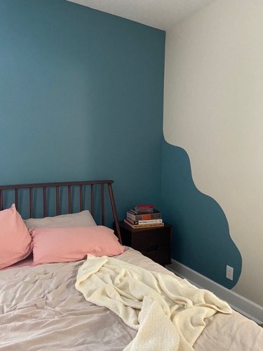 bed with neutral bedding and pink pillows near wavy accent wall