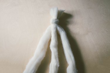 Three strands of ivory wool roving knotted together