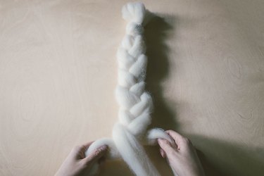 Braiding three strands of wool roving together