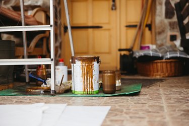Paint tools,can with brown color and filled mason glasses standing in front of a house door
