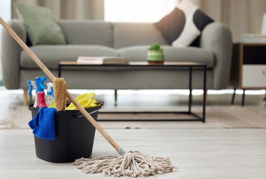 Shot of a mop and bucket of cleaning supplies on living room floor.