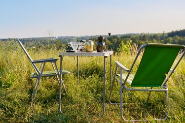 Set of folding furniture for camping, table and chair, summer nature of wild meadow