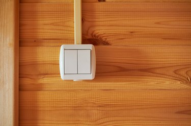Double white plastic light switch on wooded wall. Electric equipment of house. Close up view with copy space for the text.
