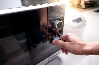 Male hand turning temperature knob of microwave