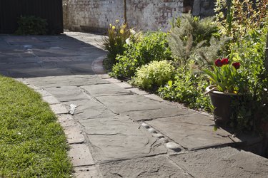 Paving of reclaimed limestone, bricks and cobbles in a domestic garden.