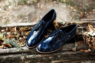 Top view of stylish and elegant patent leather brogues shoes or shoes on old wood retaining wall with autumn leaves.