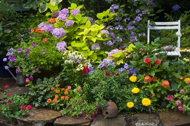 Colorful flower garden with pavers and chair.