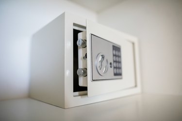 Metal safe on a shelf inside an empty white closet