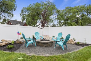 Four plastic turquoise chairs surrounding neat fire pit