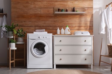 Laundry room interior with washing machine and stylish furniture.