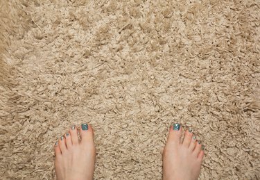 Woman feet standing on beige carpet in bathroom