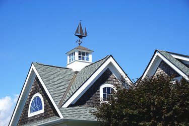 Iconic sailing ship weather vane mounted atop a white cupola on a classic gabled New England rooftop